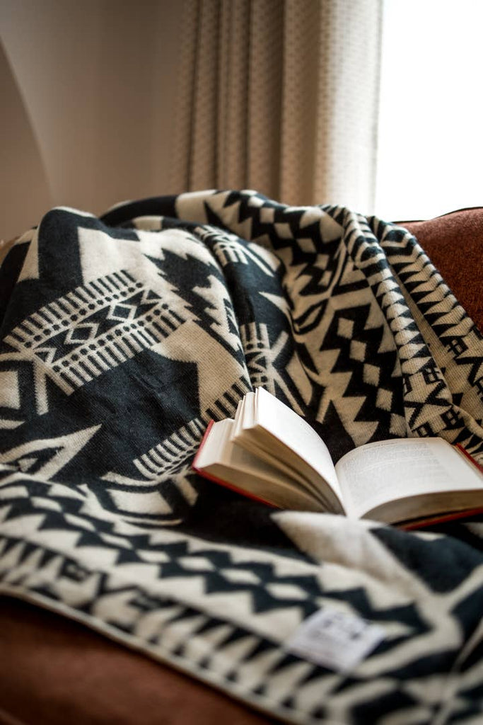 Tribal geometric print blanket made in the highlands in Ecuador with recycled acrylic. By Beyond Borders Collective. Colors include black and beige.