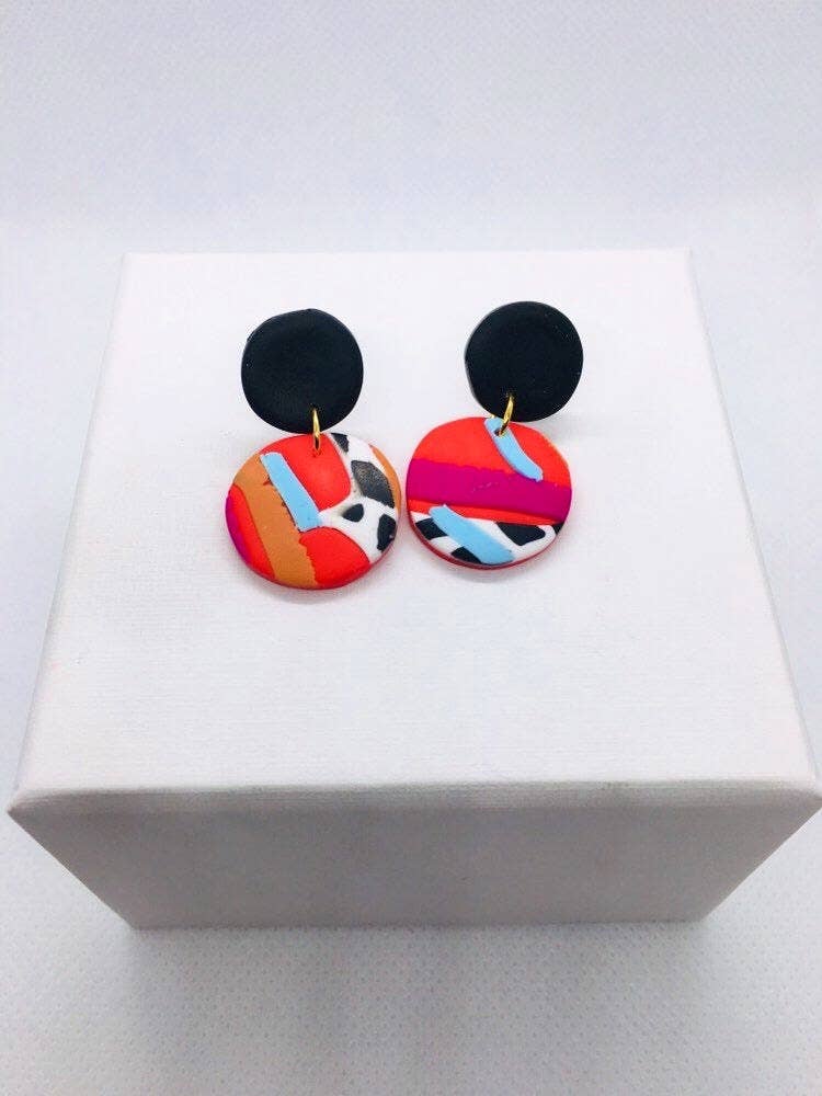 Multicolored round drop polymer clay earrings. Please note that earrings are cut from one large design, so patterns will vary slightly with each pair. Made with silver-plated, nickel-free findings. Measures 3.5 cm in length and 2 cm in width with a 2.5 cm drop.